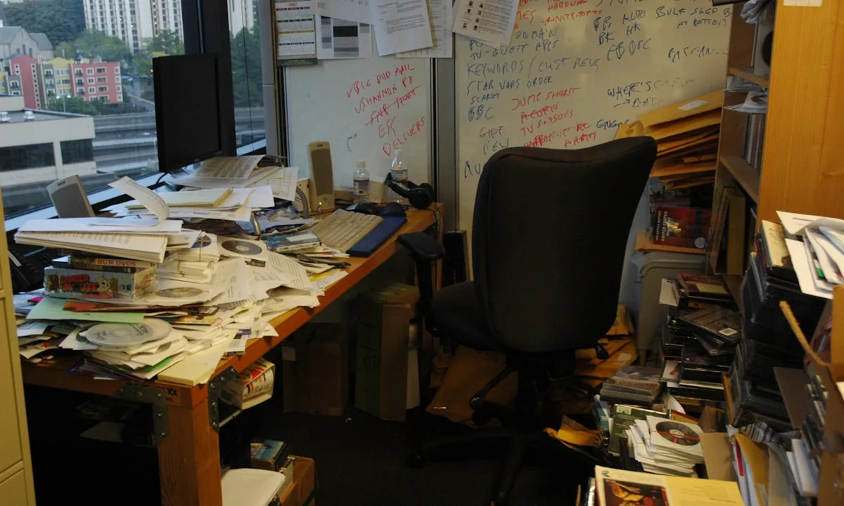 A highly disorganized desk covered in papers and coffee cups
