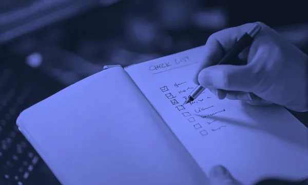 A hand confidently checking off a specific task on a notebook