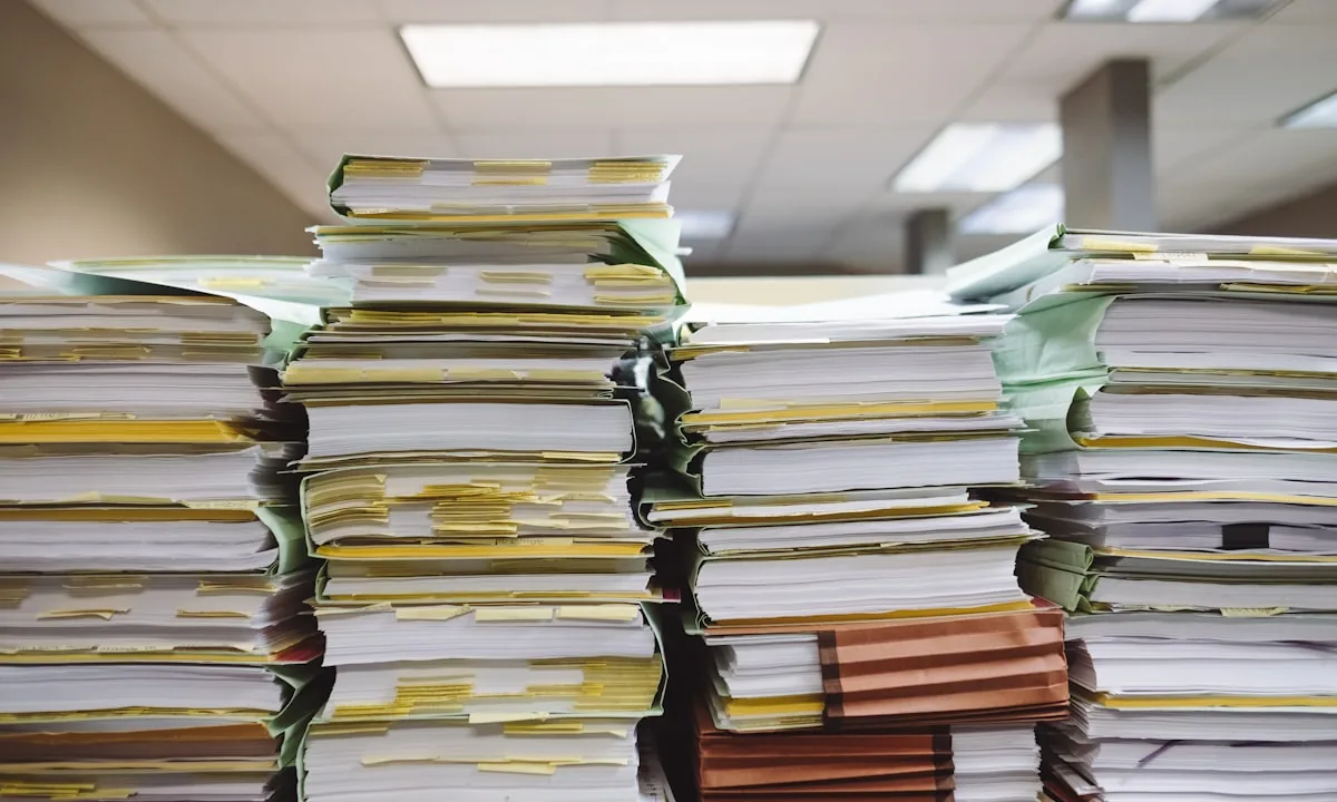 A massive stack of paperwork symbolizing the overwhelming amount of AI-generated code that needs review.