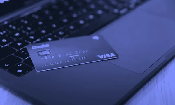 Person typing on a laptop with a credit card nearby