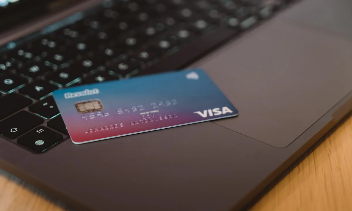 Person typing on a laptop with a credit card nearby