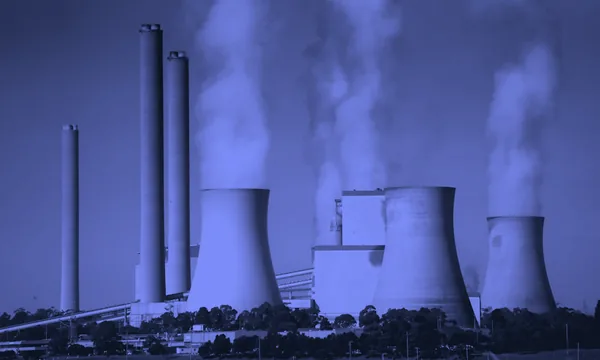Cooling towers of a nuclear power plant emitting steam against a blue sky