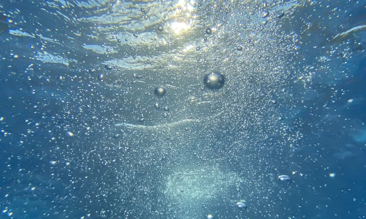 Air bubbles expanding and bursting underwater, resembling cavitation.