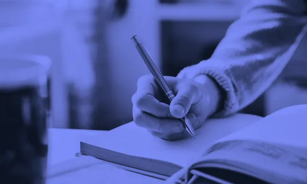 Person writing down their main goal in a journal