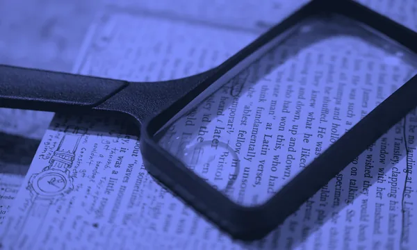 A magnifying glass inspecting small text on a paper document
