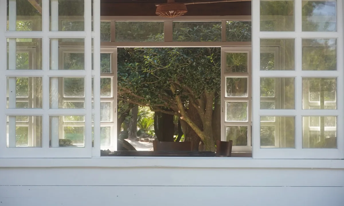 An open notebook with a pen sitting beside a window overlooking a quiet garden