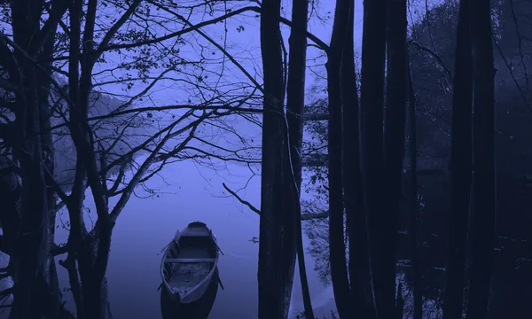 A small wooden boat resting on a calm misty lake at dawn