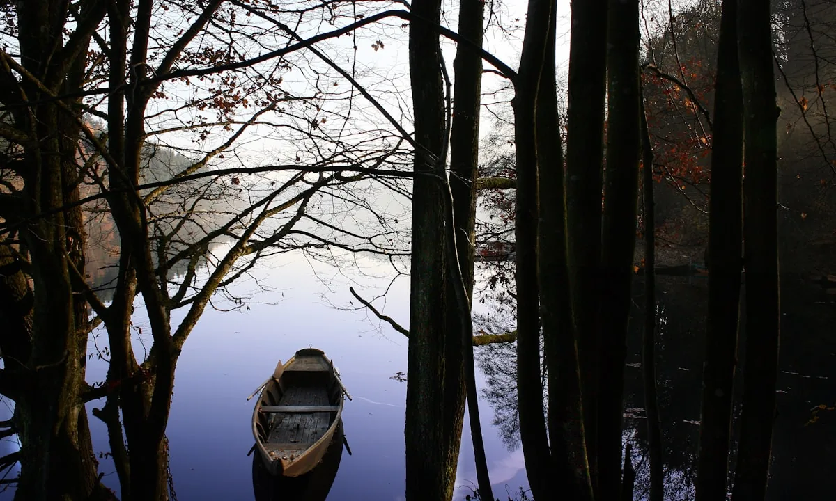 A small wooden boat resting on a calm misty lake at dawn