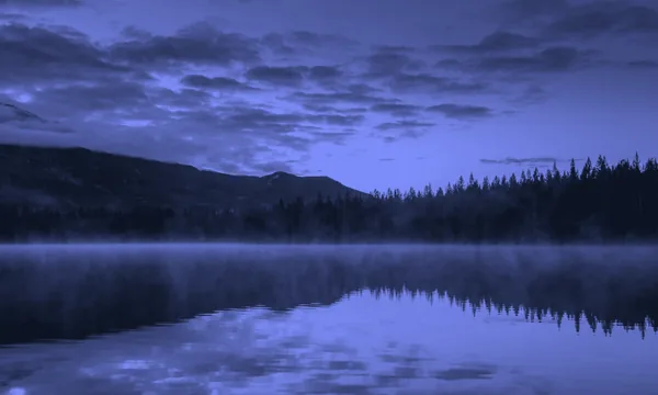 A calm lake reflecting clear skies and quiet hills