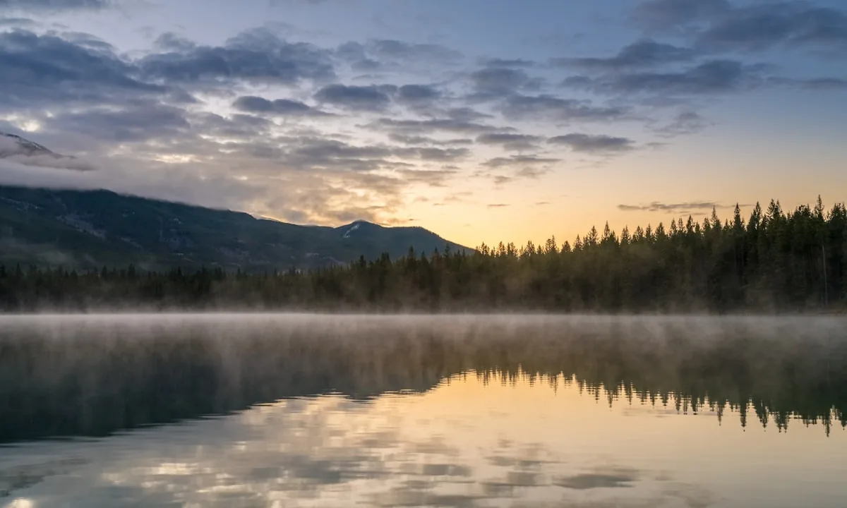 A calm lake reflecting clear skies and quiet hills
